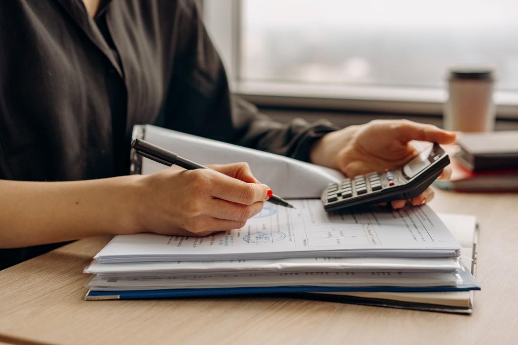 Professional reviewing stamped financial documents with a calculator while preparing evidence for a contract loss claim